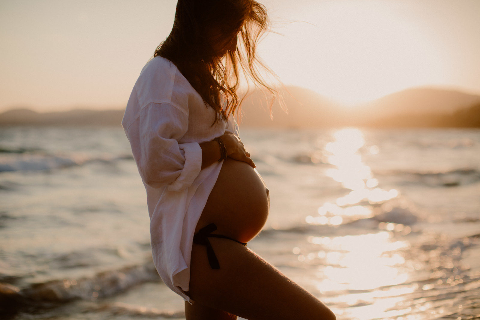 femme enceinte au bord de la mer avec un coucher de soleil sur la plage de Gigaro