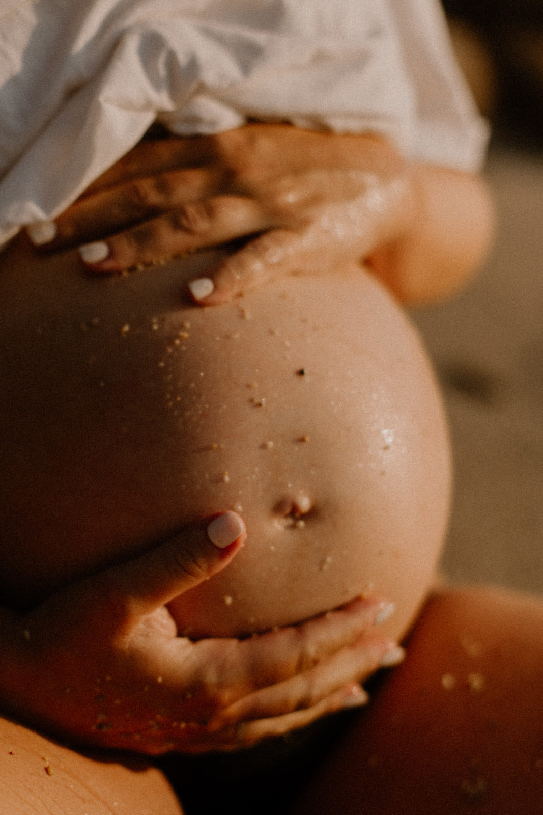 Photographe de grossesse et ventre rond dans le sable