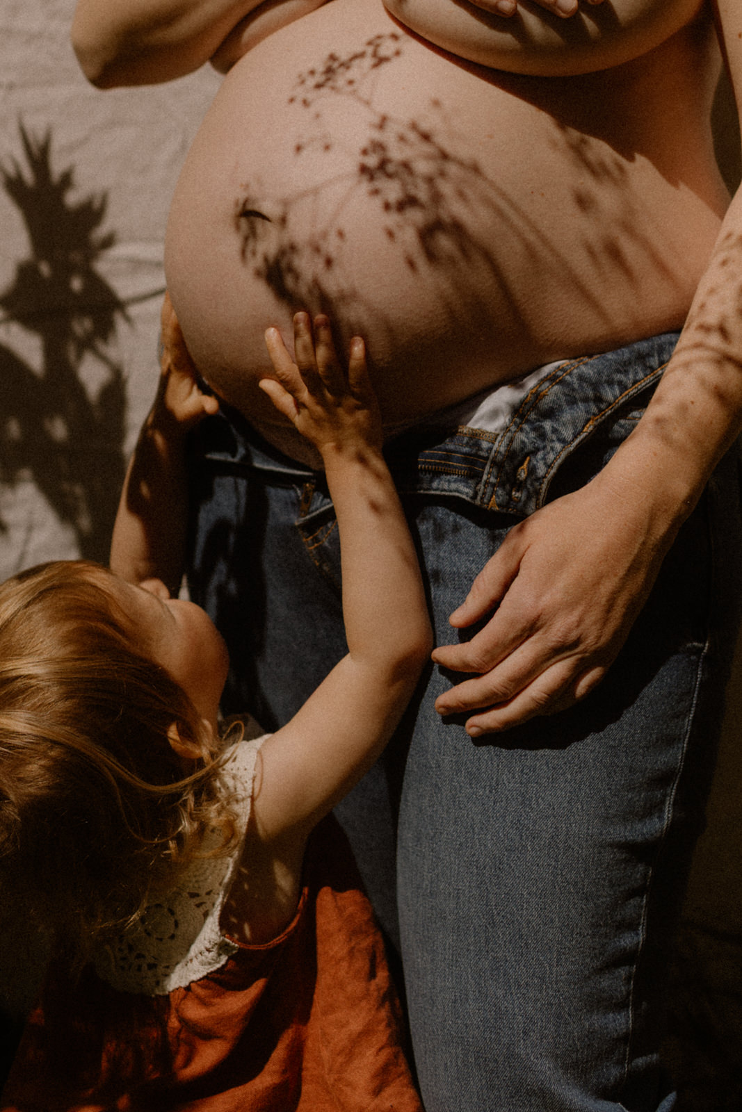 Photographie d'un ventre de grossesse avec une ombre et la main d'un bébé. Photo publiée dans Vogue